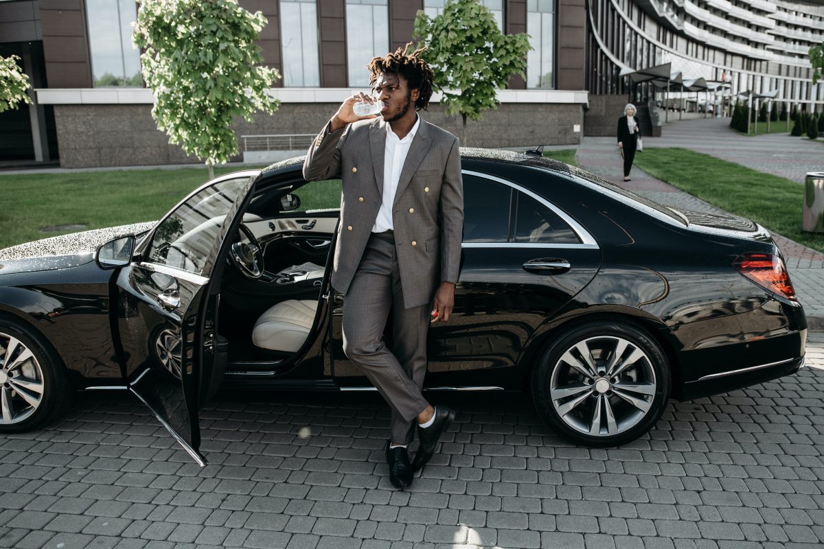 A person posing next to a car.