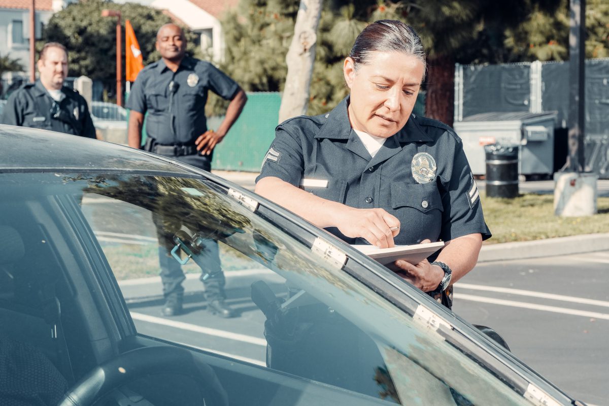 A police officer writing a ticket for a parked car.