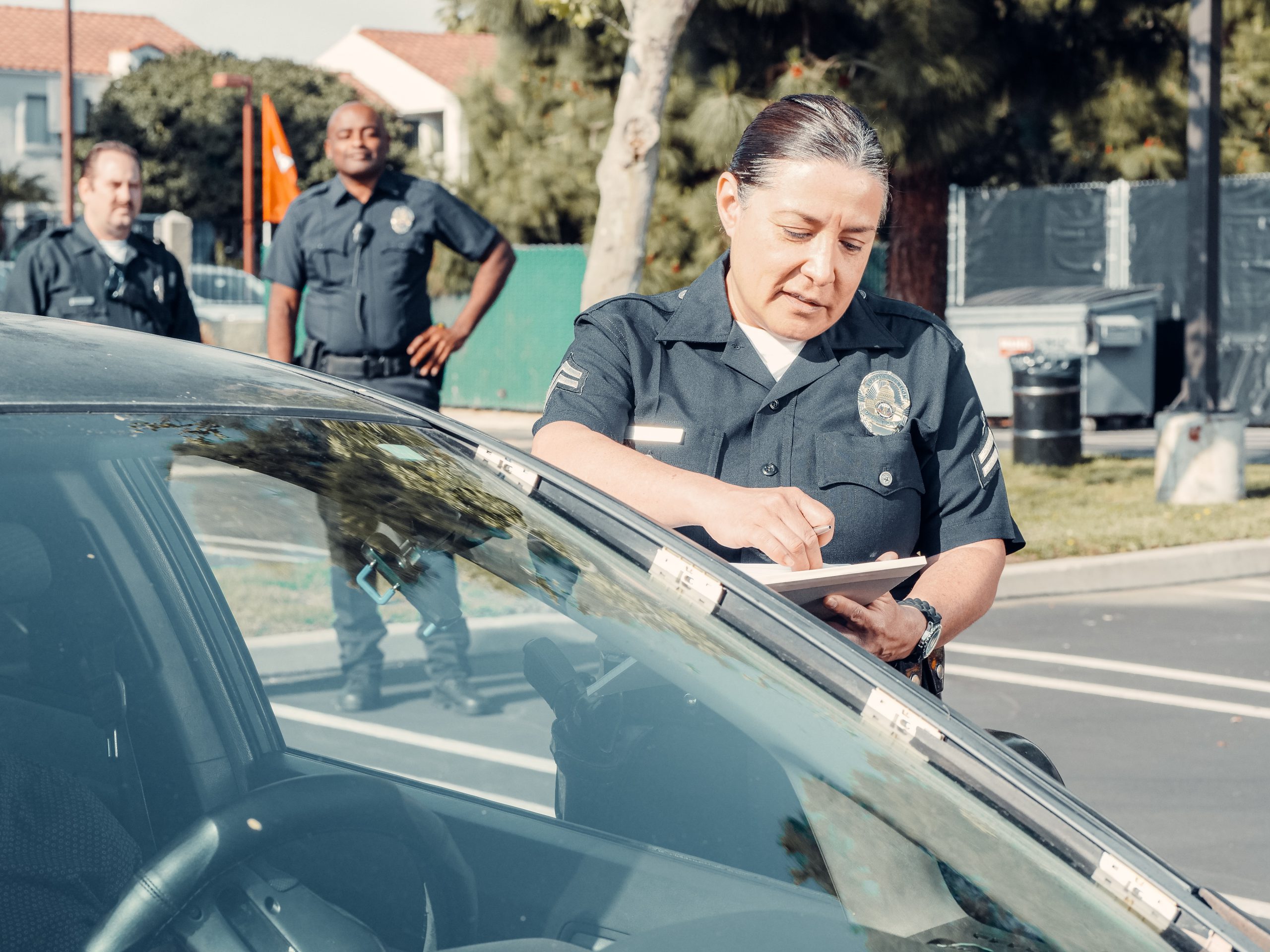 A police officer writing a ticket for a parked car.