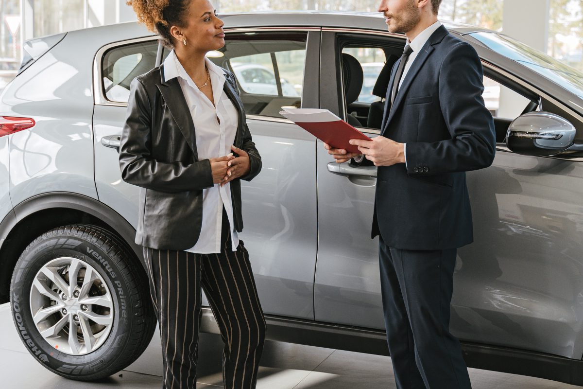 Two people having a discussion next to a parked car.