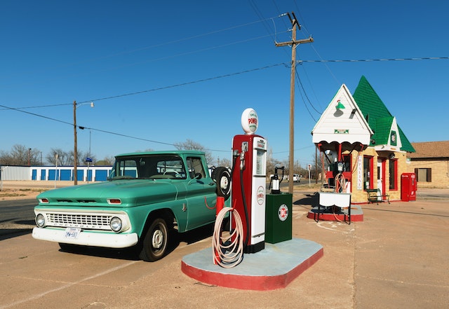 A vintage car next to a gas pump.