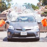 People throwing buckets of water on a car.