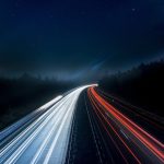 Lights shining on a dark highway at night.