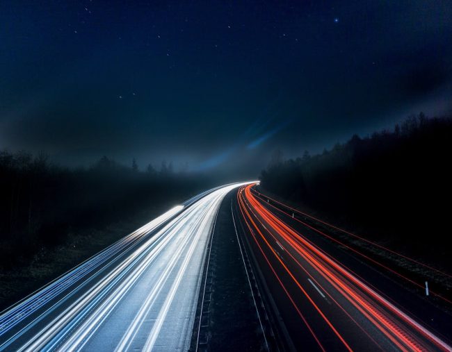 Lights shining on a dark highway at night.