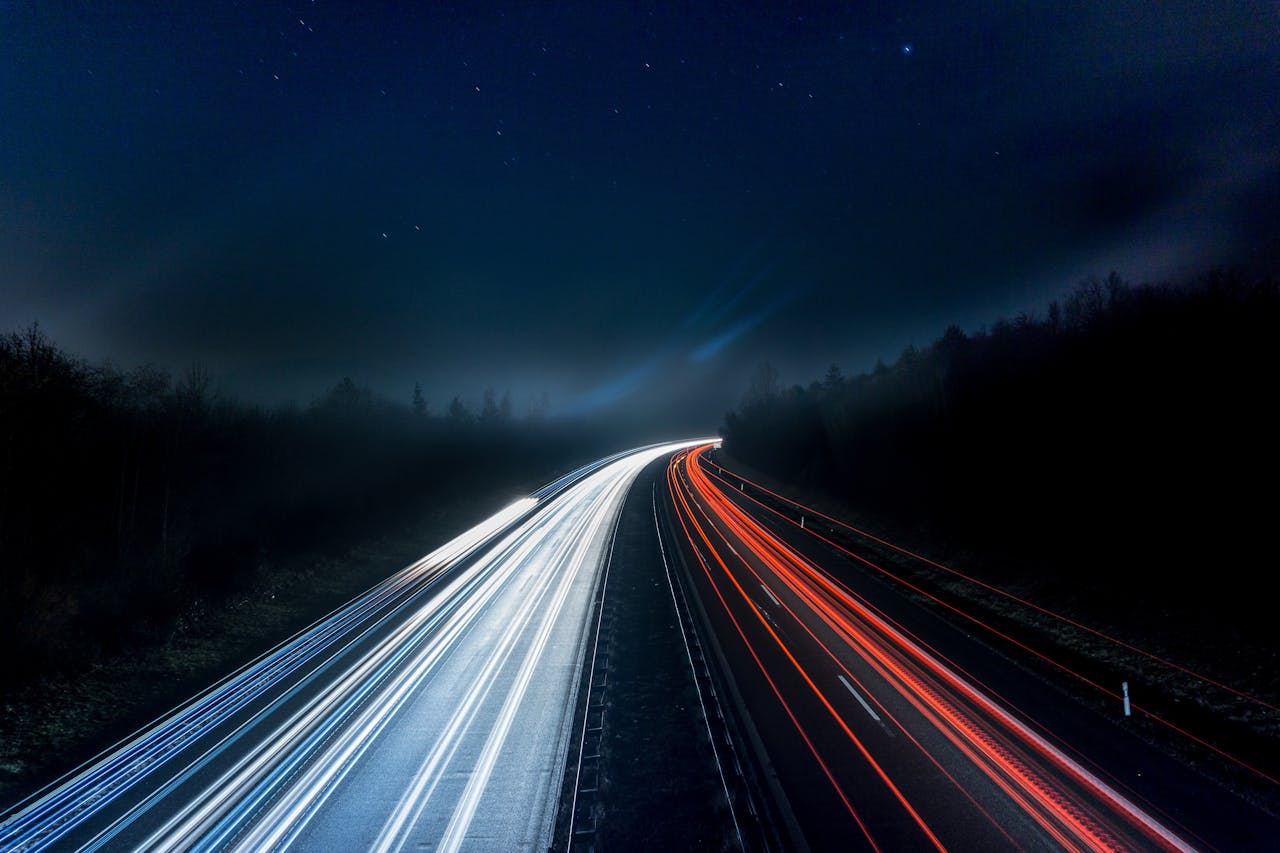 Lights shining on a dark highway at night.