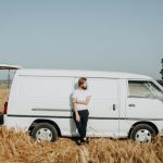 A man leaning on a large white van.