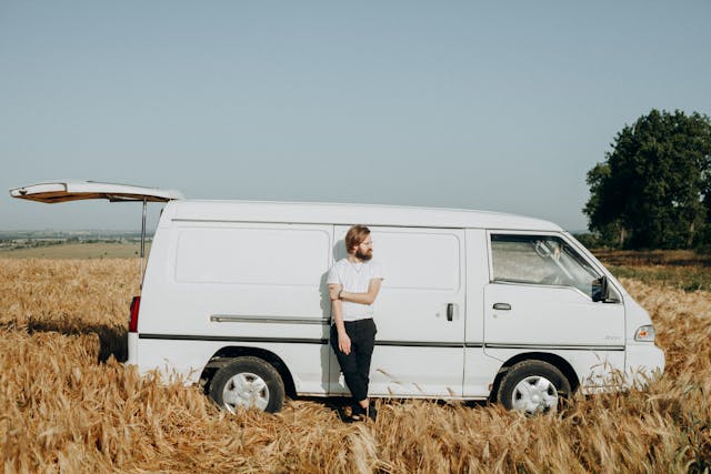 A man leaning on a large white van.