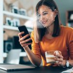 Facial recognition software, on a phone, scanning a woman's face.