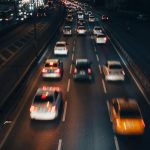 A photo of cars driving down the road at night.