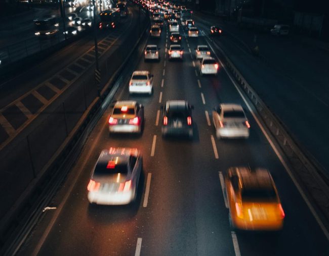 A photo of cars driving down the road at night.