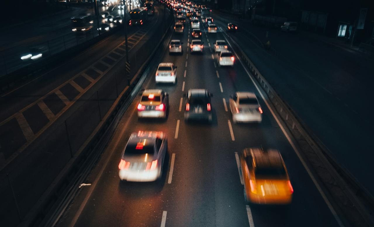 A photo of cars driving down the road at night.