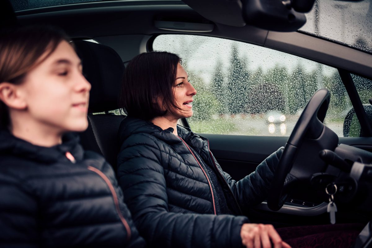 A woman driving with her daughter in the passenger seat. It's raining.