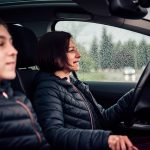 A woman driving with her daughter in the passenger seat. It's raining.